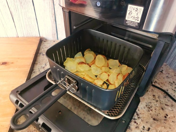 Uma airfryer contendo batatas fatiadas.
