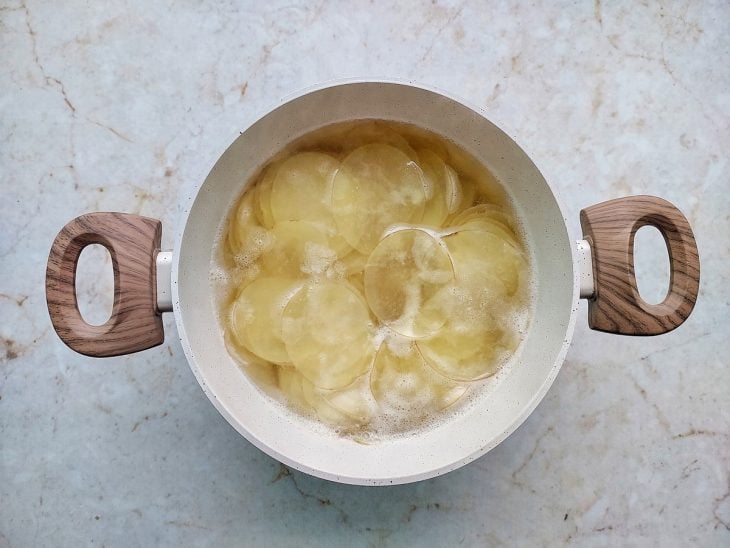 Lâminas de batatas transferidas para panela com água.
