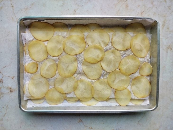 Laminas de batatas secando em forma com papel toalha.