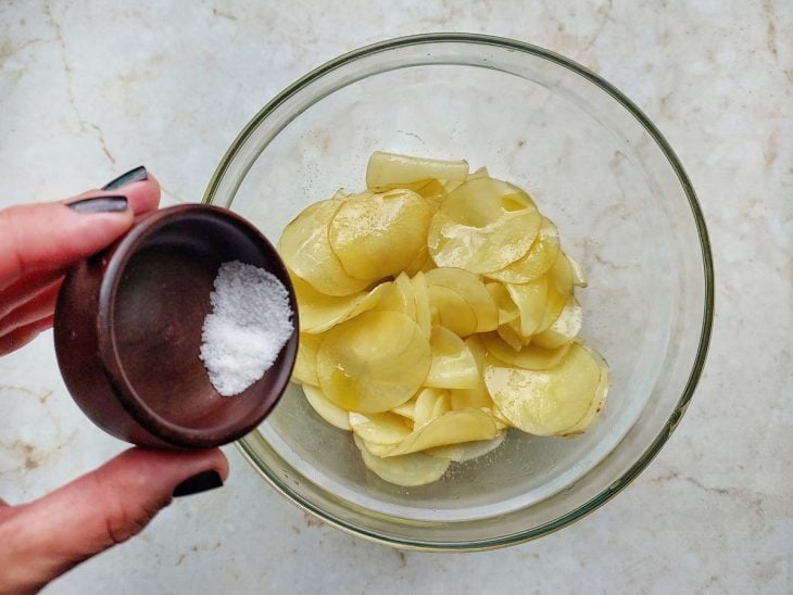 Batatas sendo temperadas com azeite e sal.