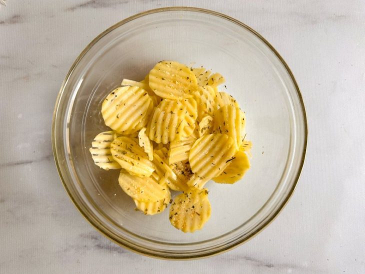 Numa tigela, as rodelas de batata já temperadas.