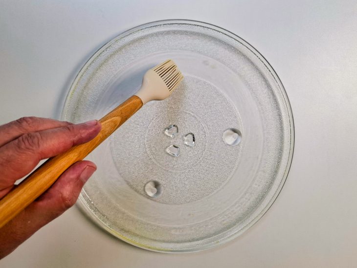 Prato do micro-ondas sendo untado.