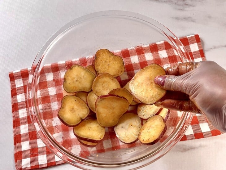 Um recipiente contendo batatas-doces fatiadas e temperadas.