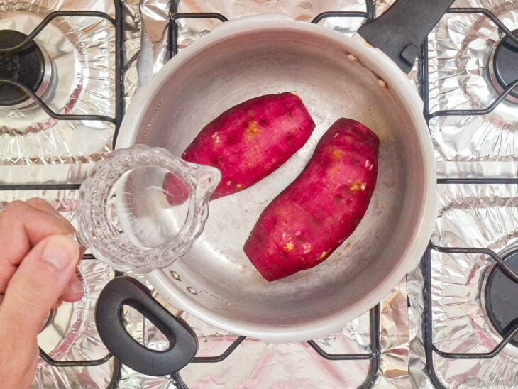 Batatas na panela, água sendo adicionada.