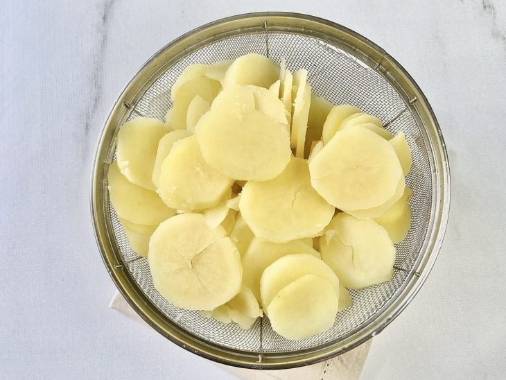 Rodelas de batatas cozidas em uma peneira.