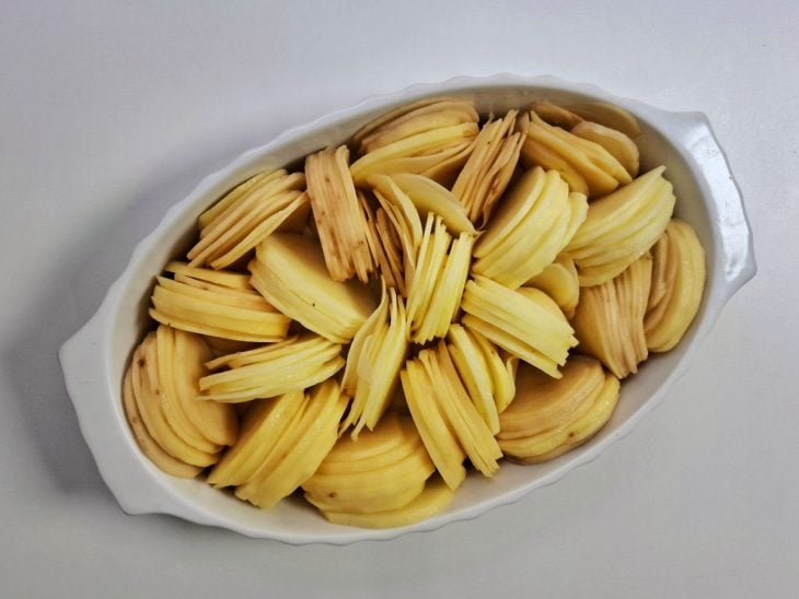 Um refratário com as batatas em rodelas.