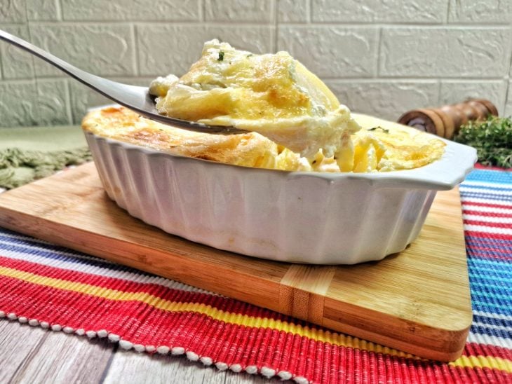 Um refratário com a batata gratinada com requeijão.