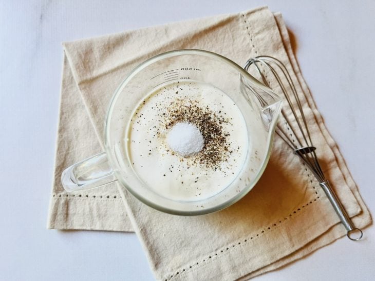 Tigela com creme de leite, sal, noz-moscada e pimenta.