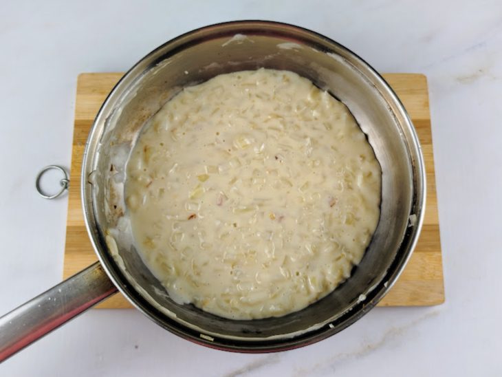 Panela com a mistura de leite com amido, requeijão, alho, cebola, água e sal.