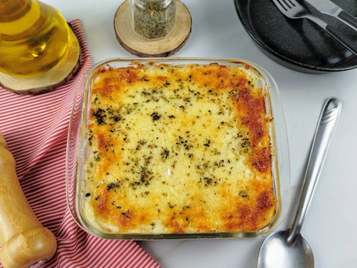 Batata gratinada pronta para consumo em uma travessa de vidro.