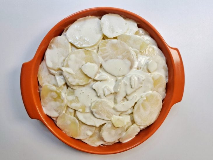 Refratário com as batatas cozidas e o creme temperado.