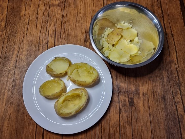 4 batatas com o miolo retirado em uma tigela ao lado.