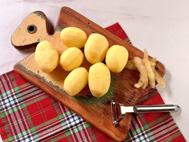 Uma tábua contendo batatas descascadas.
