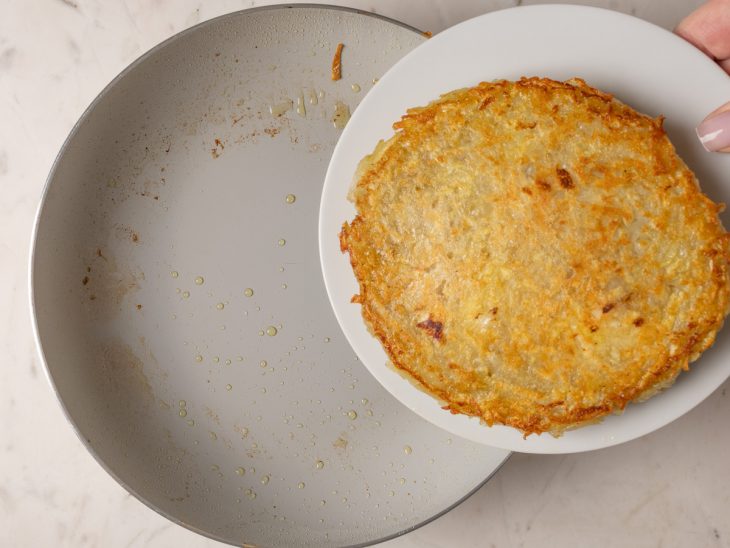 batata rosti virada com auxílio de um prato.