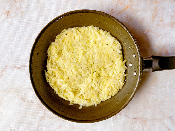batata ralada espalhada pela frigideira.