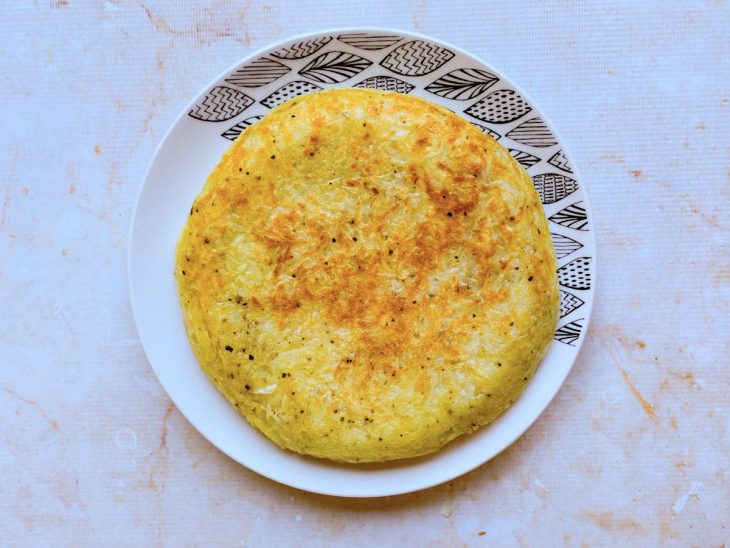 batata rosti virada com auxílio de um prato para dourar o outro lado.