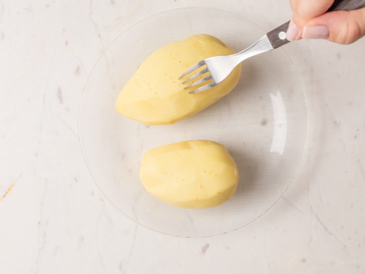 Batatas cozidas com furinhos feitos por um garfo.