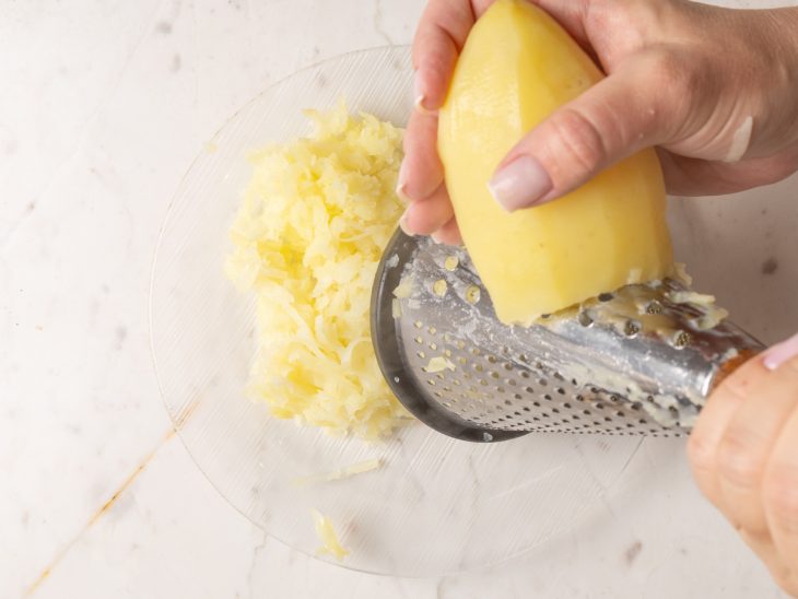 Batata sendo ralada em um prato.