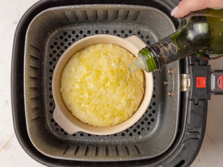 Recipiente com a batata rosti dentro do cesto da air fryer.