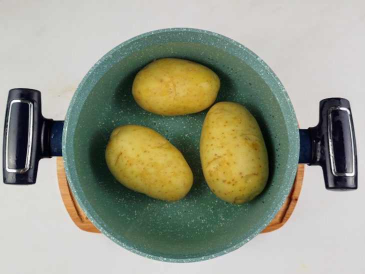 Batatas higienizadas colocadas numa panela com água para cozinhar.