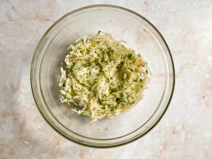 Tigela com batata ralada, sal, páprica, pimenta-do-reino e cheiro verde.
