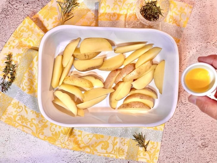 Batatas rústicas espalhadas em uma assadeira.