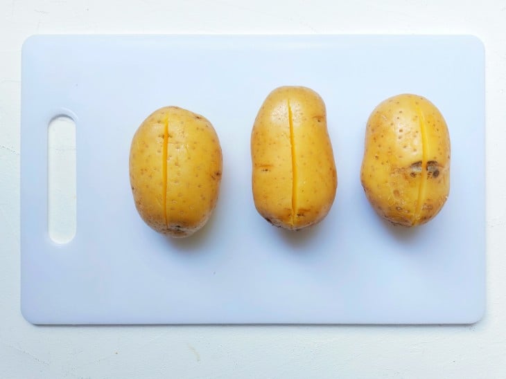 Três batatas inteiras com um corte reto.