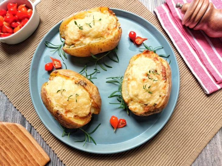 Batatas rústicas recheadas dispostas em um prato azulado.