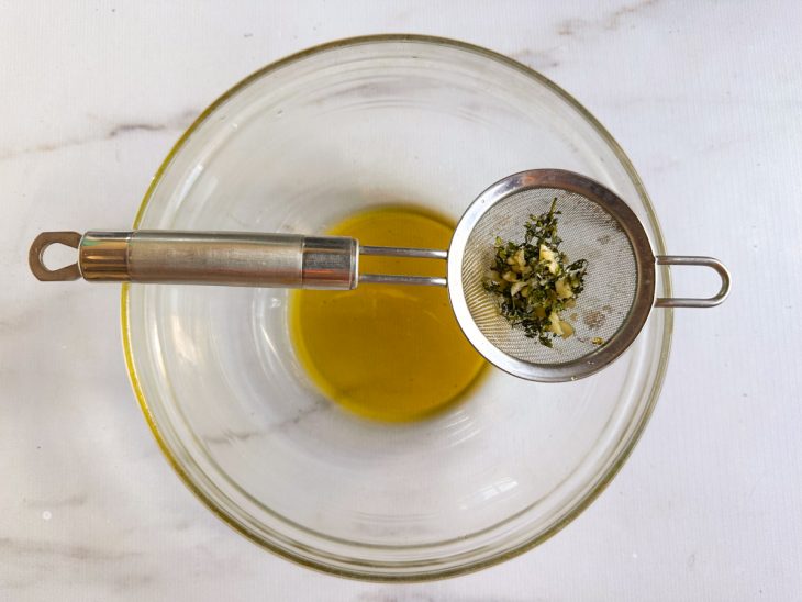 Batatas envolvidas com o azeite aromatizado em uma tigela.