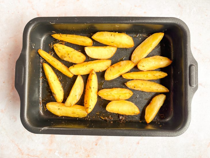 Batatas dispostas em assadeira com a casca voltada para baixo.