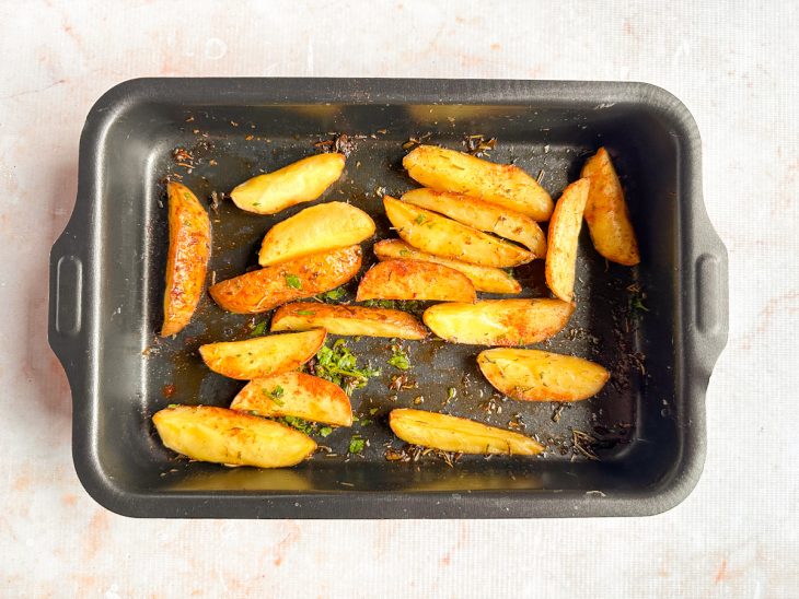 Batatas assadas, douradas e crocantes na assadeira.