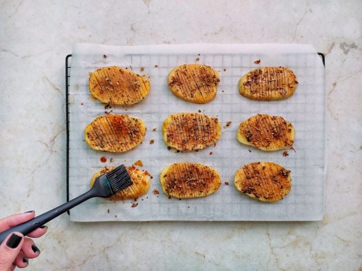 Fatias de batata pinceladas com o molho de azeite e condimentos.