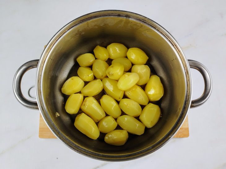 Uma panela com manteiga, azeite, alho, batatas.