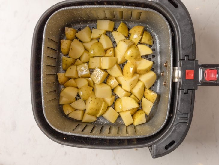 Air fryer com batatas temperadas.