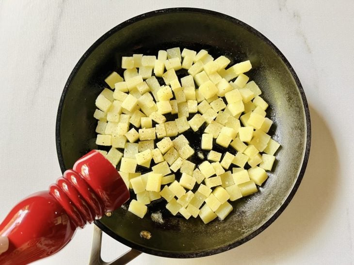 Uma frigideira com as batatas temperadas.