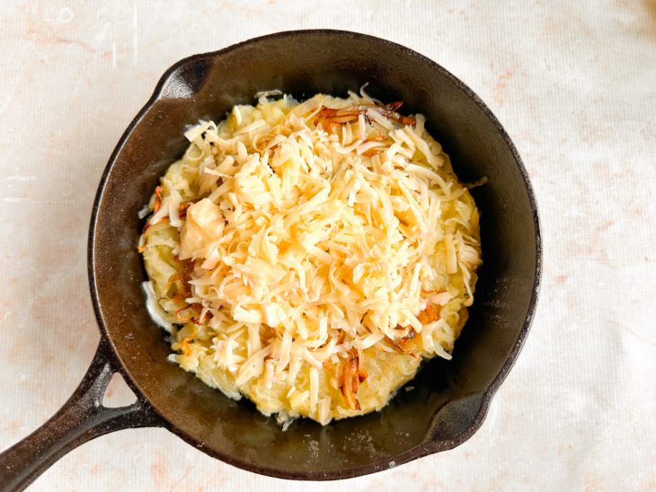 Camada de cebola e queijo por cima das batatas.