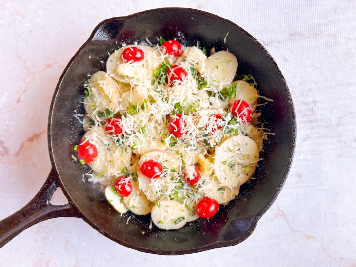 Tomates, queijo e temperos adicionados às batatas.