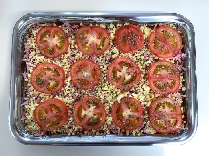 Camada de presunto, queijo, tomate e orégano por cima dos pães.