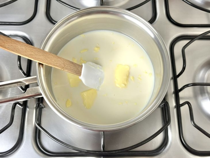 Uma panela ao fogo com leite condensado, leite e manteiga.