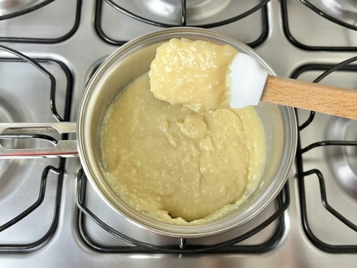 Uma panela ao fogo com leite condensado, leite, manteiga e coco ralado.
