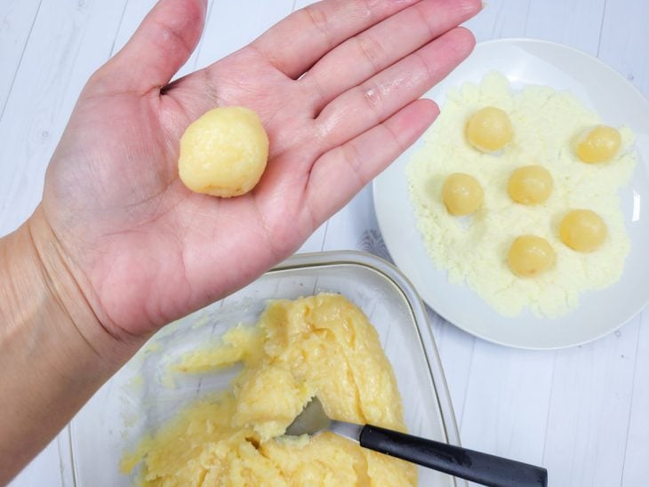 Um recipiente com a mistura de beijinho sendo enrolada.