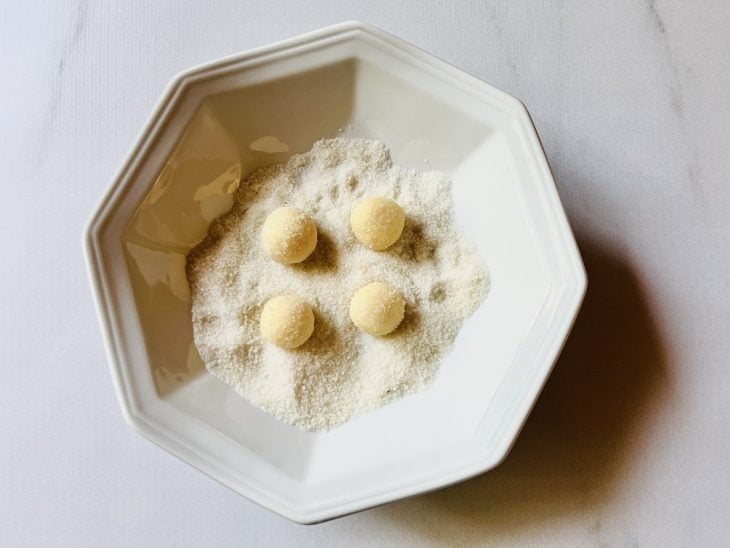 Beijinhos enrolados em um prato com açúcar cristal.
