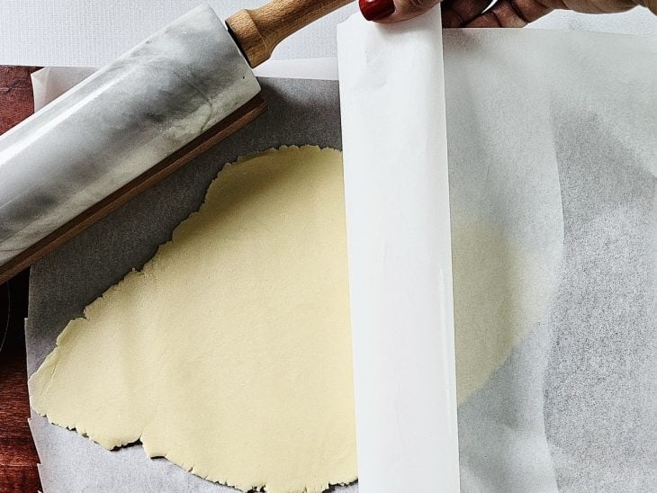 Massa aberta com um rolo e forrada com papel-manteiga.