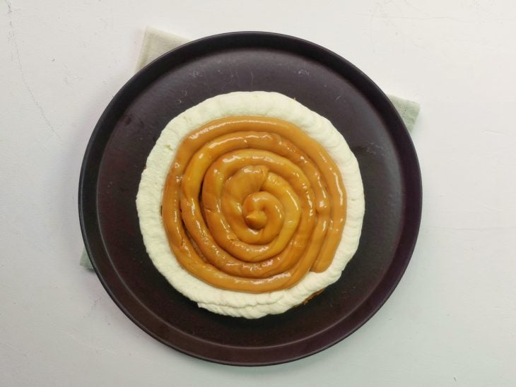 Um bolo com as boradas cobertas com chantininho e doce de leite no meio.