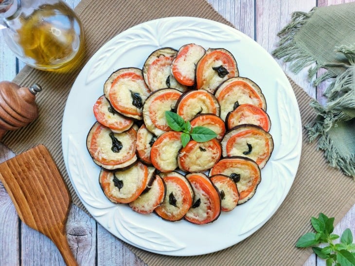 Um prato com berinjelas assadas com tomate e parmesão.