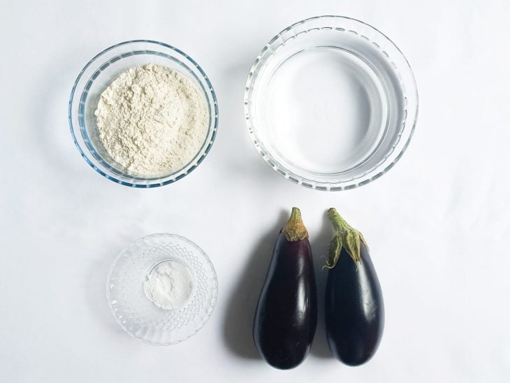Ingredientes para a receita de berinjela empanada com farinha de trigo reunidos em uma bancada.