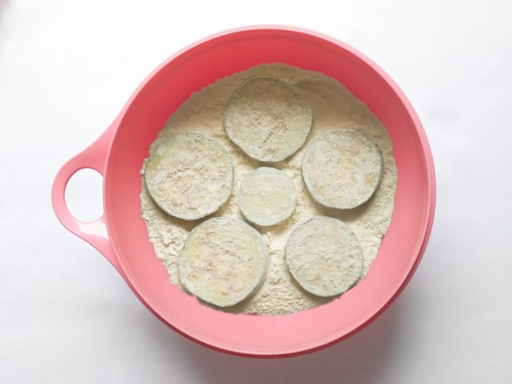 Fatias de berinjela empanadas na farinha de trigo.