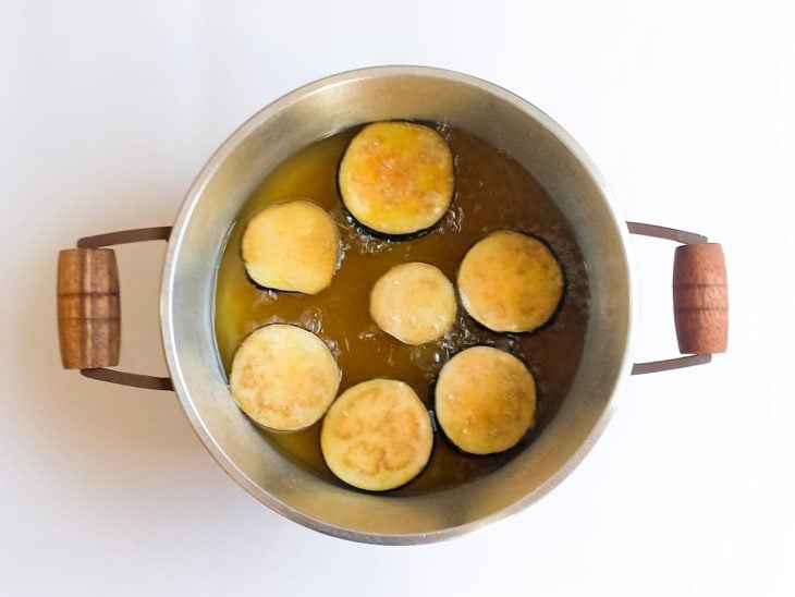 Fatias de berinjela empanada em óleo quente para fritar.
