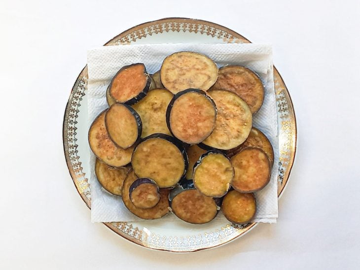 Fatias de berinjela acomodadas em um prato forrado com papel-toalha.