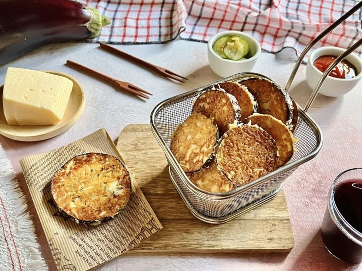Um recipiente contendo berinjela empanada com queijo.